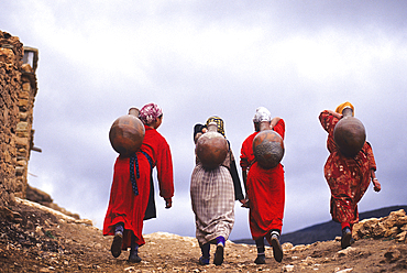 Women carrying water in jar on their back from spring to the village Imi n Tala,High Atlas,Morocco,North Africa