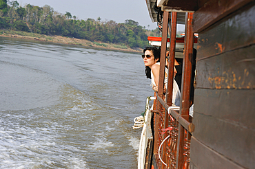 Young woman standing at the railing of a cruise boat, owned by ' The Luang Say Lodge & Cruises',on Mekong River, between Pakbeng and Luang Prabang, Oudomxay Province, Laos, Southeast Asia