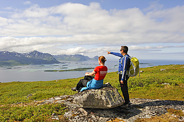 Trekkers having a break with view over the fjord Bergsfjorden from Husfjellet mountain, Senja island, County of Troms, Norway, Northern Europe