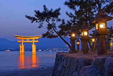 Stone lanterns and the iconic torii at the Itsukushima Shrine, on Miyajima island, hiroshima Prefecture, Japan