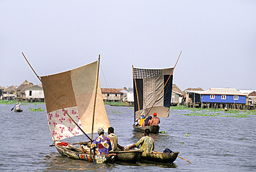 Villagers moving by sailing pirogue on Ganvie lake village in Lake Nokoué, near Cotonou, Gulf of Guinea, West Africa