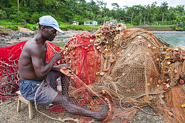 Man mending fishing net at Porto Alegre village in the south of Sao Tome Island, Republic of Sao Tome and Principe,Africa