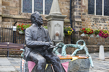 Bronze statue of Victor Hugo sitting on a granite bench, by the artist Mark Cook, in front of the Town Church, St Peter Port, Guernsey Island, Bailiwick of Guernsey, United Kingdom