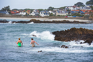 Two women going to swim at Cobo Bay on the west coast of Guernsey Island, Bailiwick of Guernsey, United Kingdom
