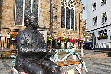 Bronze statue of Victor Hugo sitting on a granite bench, by the artist Mark Cook, in front of the Town Church, St Peter Port, Guernsey Island, Bailiwick of Guernsey, United Kingdom