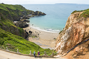 Two women looking at the Grande Greve Bay from La Coupée, the narrow isthmus which links Greater and Little Sark, Sark island, Channel Islands, Bailiwick of Guernsey, United Kingdom