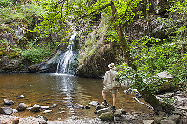 Man admiring the waterfall of Gour Saillant fed by the Auzelle, a sub-tributary of the Sioule River, Saint-Priest-des-Champs, Puy-de-Dome department, Auvergne-Rhone-Alpes region, France, Europe