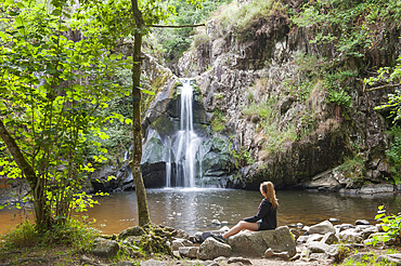 Young girl admiring the Waterfall of Gour Saillant fed by the Auzelle, a sub-tributary of the Sioule River, Saint-Priest-des-Champs, Puy-de-Dome department, Auvergne-Rhone-Alpes region, France, Europe