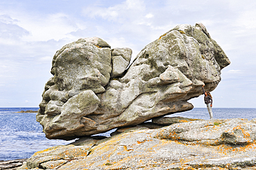 Young girl simulating holding one of the remarkable rocks on Ile de Sein,off the coast of Pointe du Raz,Finistere department,Brittany region,west of France,western Europe