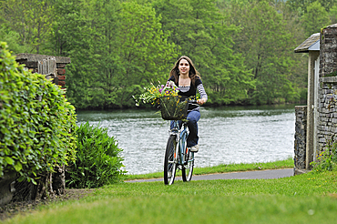Young woman cycling on cycle lane along the Meuse River at Haybes,Ardennes department,Champagne-Ardenne region of northeasthern France,Europe