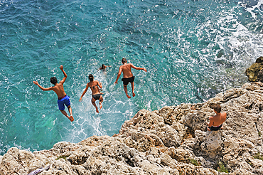 Teenagers diving into the mediterranean sea from the rocky coast near Roquebrune-Cap-Martin, Alpes-Maritimes department,Provence-Alpes-Cote d'Azur region,southeast of France,Europe.