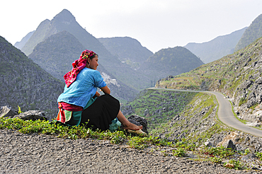 jeune femme assise au bord d'une route de montagne,environs de Sa Phin,plateau de Dong Van,province de Ha Giang,nord Vietnam,asie du sud-est//young woman sitting on the side of a mountain road,around Sa Phin,Dong Van plateau,Ha Giang province,northern Vie