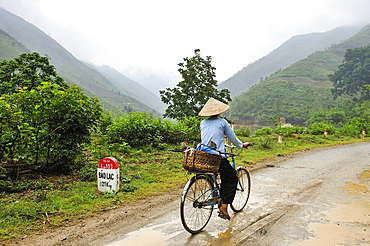 Woman riding bike coming from the market of Coc Pang village, Cao Bang province, Northern Vietnam, Southeast Asia