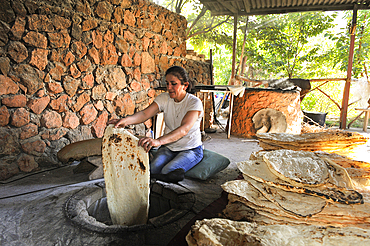 Woman making lavash (thin unleavened flatbread) made in a tandoor, called tonir in Armenian, in a restaurant beside the Noravank Monastery, near Yeghegnadzor, Armenia, Eurasia