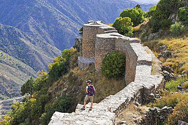 Young woman standing on a defensive wall of Smbataberd Fortress, on the crest of a hill between the villages of Artabuynk and Yeghegis, near Yeghegnadzor, Vayots Dzor province, Armenia, Eurasia