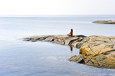 Woman standing on rock at the confluence of Saguenay and Saint Lawrence rivers, Tadoussac, Cote-Nord region, Province of Quebec, Canada, North America