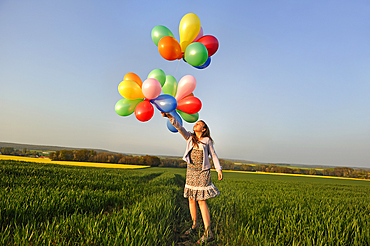 Little girl playing with balloons in the fields, Eure-et-Loir department, Centre region, France, Europe