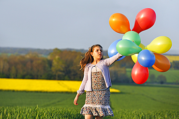 Little girl playing with balloons in the fields, Eure-et-Loir department, Centre region, France, Europe