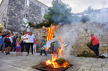 Young boys jumping over a wood fire beside the Cathedral St. Marka, Korcula old town, Korcula island, Croatia, Southeast Europe