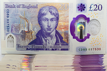 A close-up of a £20 British banknote featuring a portrait of a historical figure, with intricate security features and holograms visible.