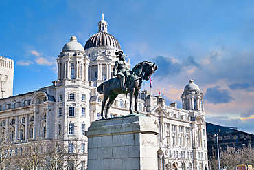 Equestrian statue of King Edward VII in front of the Royal Liver Building in Liverpool, under a partly cloudy sky in Liverpool, UK.