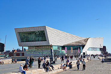 Wide shot: Museum of Liverpool with people on the plaza under a clear blue sky
