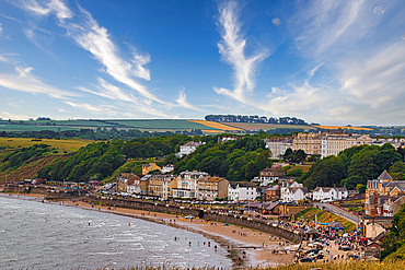 Coastal town view with beach, buildings, and fields under a blue sky with scattered clouds in Filey, UK.
