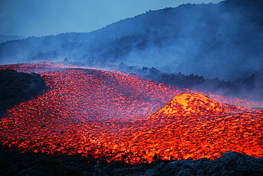 November 2006 - Boulder rolling in lava flow at dusk during eruption of Mount Etna volcano, Sicily, Italy.