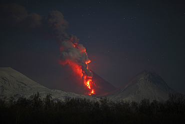 October 15, 2013 - Nighttime eruption of Kliuchevskoi (Klyuchevskoy) Volcano, Kamchatka, Russia.
Ash cloud and lava flow are produced by the activity of the snowcovered conical stratovolcano. Column of steam rises where lava flow is melting glacier.