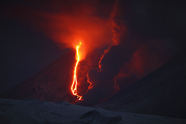 October 16, 2013 - Nighttime eruption of Kliuchevskoi (Klyuchevskoy) Volcano, Kamchatka, Russia. Ash cloud and lava flow are produced by the activity of the snowcovered conical stratovolcano. Column of steam rises where lava flow is melting glacier.
