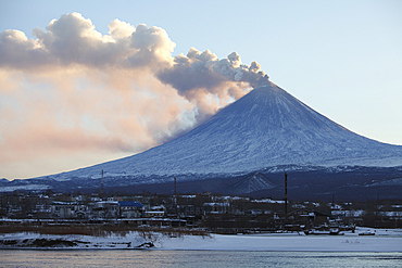 October 19, 2013 - Eruption of Kliuchevskoi (Klyuchevskoy) Volcano, Kamchatka, Russia. Ash and steam cloud are blown away by wind. View over industrial area of Kliuchi town with Kamchatka River in foreground.