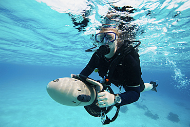 Scuba diver navigates the waters using a diver propulsion vehicle off the coast of Bonaire, Caribbean Netherlands.