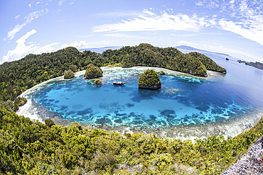 Rugged limestone islands surround a gorgeous lagoon in a remote part of Raja Ampat, Indonesia. This beautiful region is known as the heart of the Coral Triangle and is a popular destination for scuba divers and snorkelers.