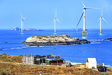 A cottage on the coast of Pingtan Island with windmills in the sea. Pingtan Island, Fuzhou City, Fujian Province, China.