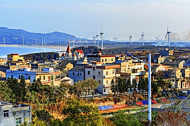 Warm sunlight on a village and windmills on the coast of Pingtan Island, Fuzhou City, Fujian Province, China.