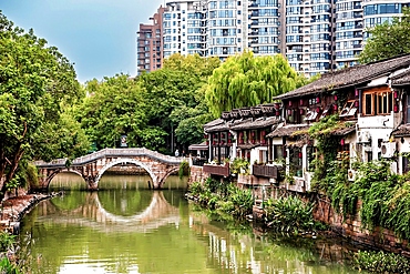 Ancient stone bridge over a smaller section of the Grand Canal with heritage buildings along its banks on Xiaohe Street (Little River Street) in Hangzhou, Zhejiang Province, China.