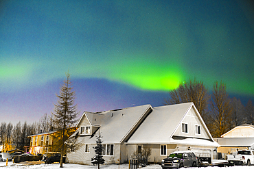 Northern lights illuminate the night sky along the horizon behind the mountains near Anchorage, Alaska, United States Of America.