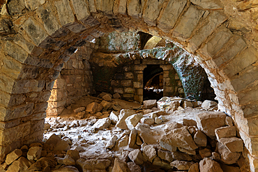 Interior of an ancient abandoned ruined stone house with arch, weathered walls, historic mysterious atmosphere.