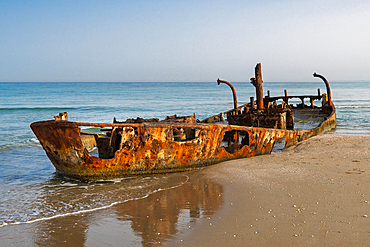 Rusted shipwreck on a Mediterranean beach in Israel near Nachsholim. A dramatic scene of decay, history, and nature by the sea. Early morning.