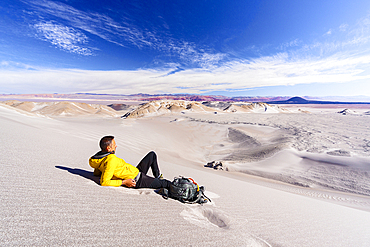 Man relaxing on white pumice dunes, Campo de Piedra Pomez, El Penon, Puna, Catamarca, Argentina. (MR)
