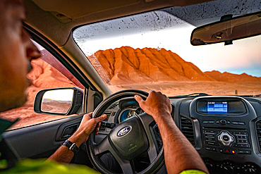 Man looking at the idyllic wild landscape from windscreen while driving an off road vehicle, Labyrinth Desert, Puna, Argentina