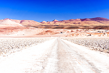 Empty desert road towards red rocky mountains, Salar de Arizaro salt flat, Puna, Argentina