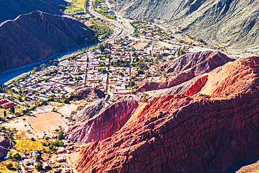 Aerial view of the ancient village of Purmamarca in a valley framed by red rocks mountains, Argentina