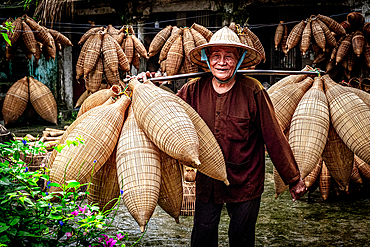 Smiling man carrying handmade fish traps, Hanoi, Vietnam. (MR)