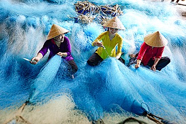 Women mending blue fishing nets, Vietnam