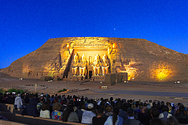 Group of tourists enjoying a sounds and lights performance illuminating the temple of Ramses II at dusk, Abu Simbel, Aswan, Egypt