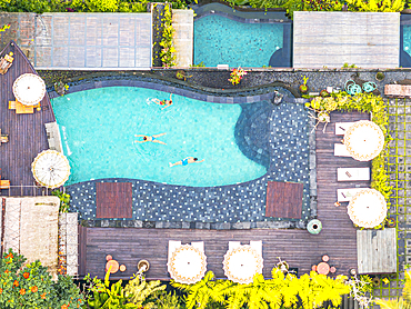 Cheerful boys with mother enjoying swimming in the pool of a luxury resort, Bali, Indonesia