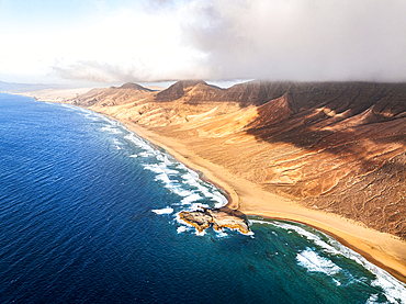 Aerial view of the wild Cofete beach in between volcanic mountains and sea, Jandia Natural Park, Fuerteventura, Canary Islands