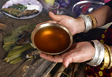 A Mishing tribal woman shows their traditional rice beer 'Aapong' during Ali-Aye-Ligang festival