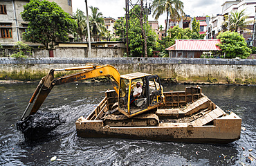 Municipality worker digging out garbage from a polluted canal using an excavator, in Guwahati, India on 27 May 2025.